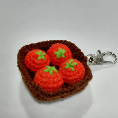 Crochet keychain of four little tomatoes on a slice of toast